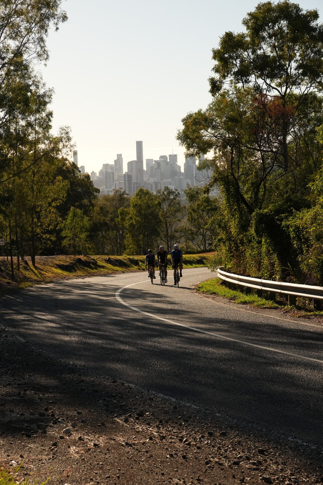 THRONE. FOUNDATION cyclists riding toward Brisbane through an Australian road setting