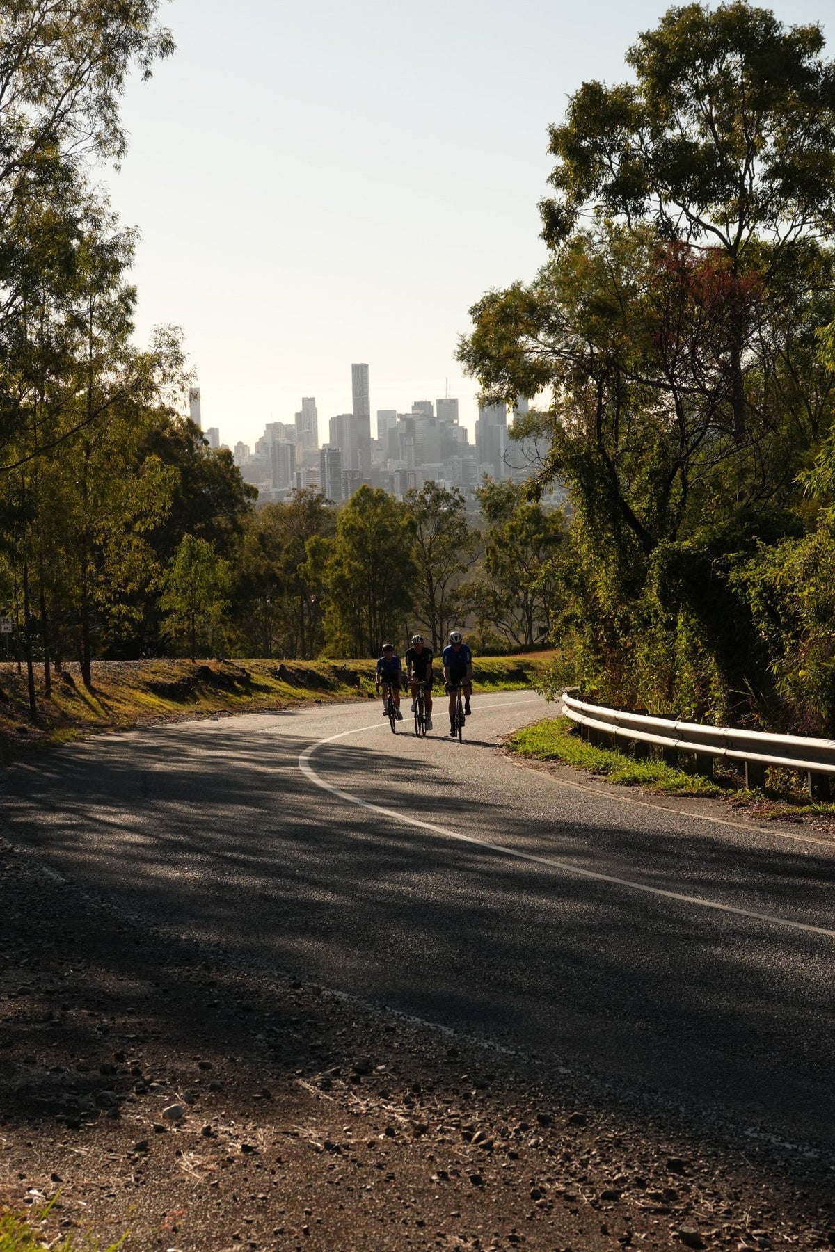 THRONE. FOUNDATION cyclists riding toward Brisbane through an Australian road setting