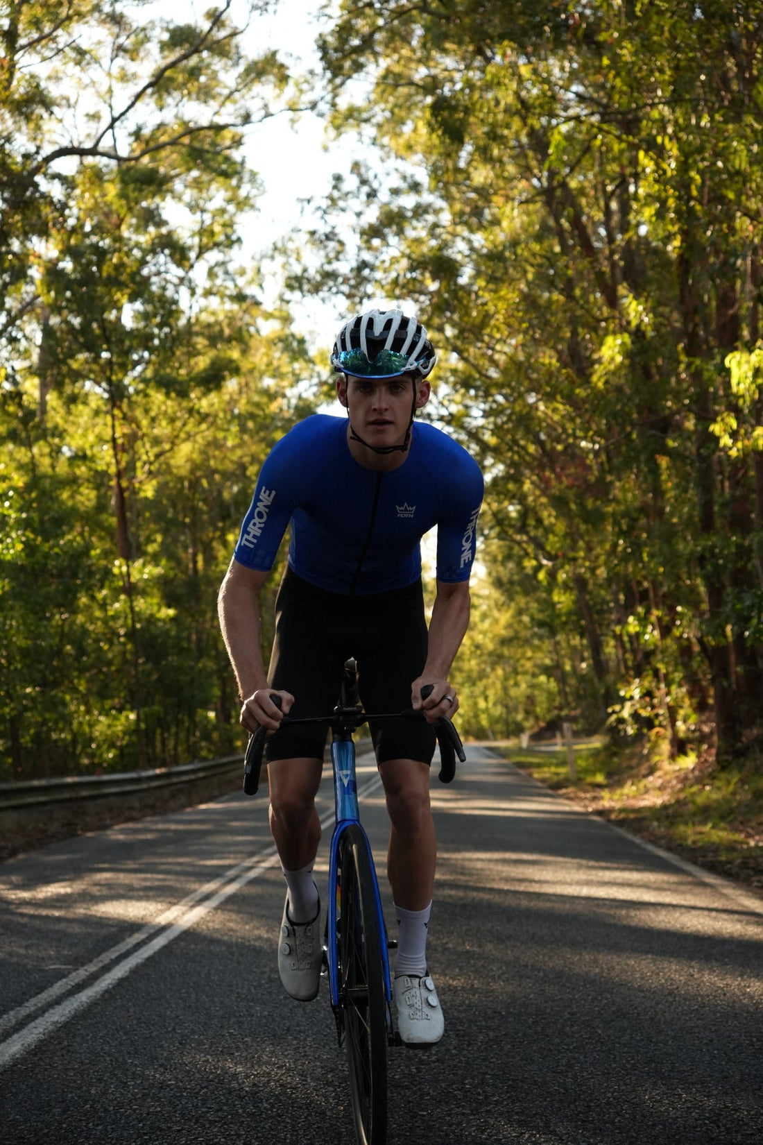 THRONE. FOUNDATION cyclist riding in the blue jersey and black bib shorts on an Australian road