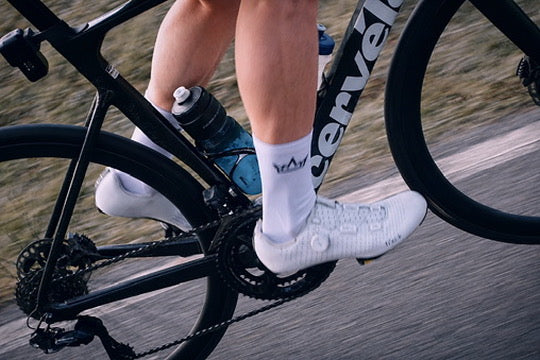 Cyclist wearing FDTN white cycling socks with crown branding on the sides